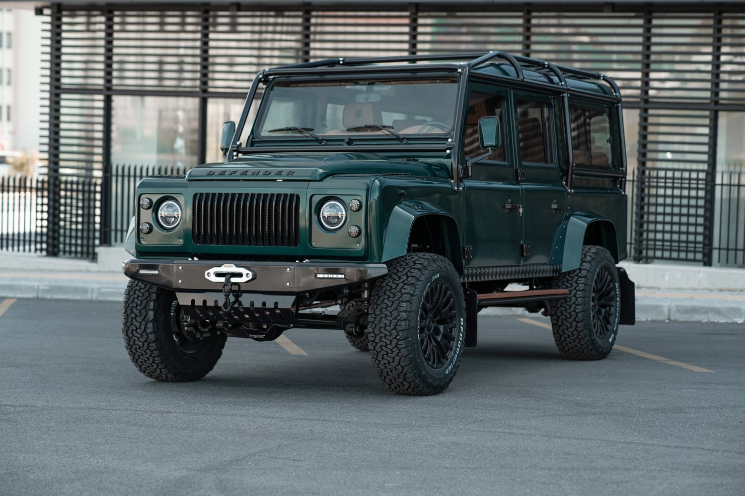 Classic vintage Land Rover Defender restored with military green paint in a scenic landscape